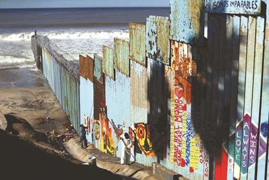 Workers paint the border wall between Mexico and US in Tijuana, Mexico, on Friday.