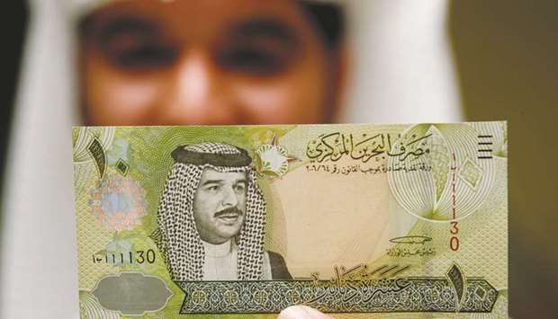 A Central Bank of Bahrain official shows a new Bahraini 10 dinars note on the first day of its release in Manama on March 17, 2008.  Investors are concerned about the governmentu2019s ability to put an austerity plan into action, with oil prices below what it needs to balance the budget.