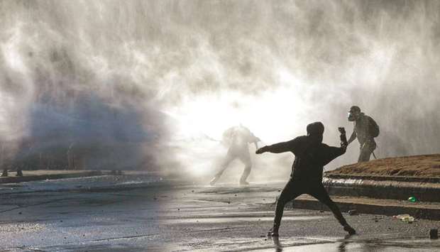 Demonstrators are hit by water cannon during a protest in Santiago.