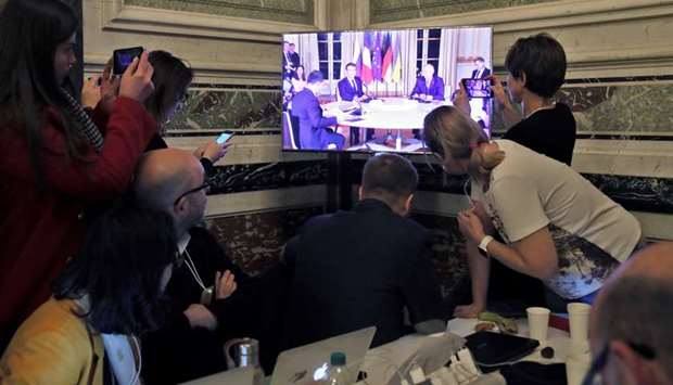 Media members watch a screen inside the press centre as Zelenskiy, Macron, Putin, and Merkel (not seen) attend a working session at the Elysee Palace.