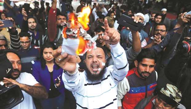 Demonstrators burn copies of the Citizenship Amendment Bill during a protest in New Delhi yesterday. Protesters in the northeast clashed with police, set fire to tyres and cut down trees to block roads  in a shutdown across the region against the Bill .