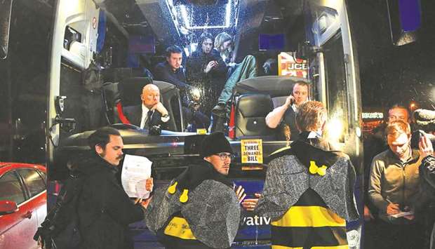 Activists from climate action group Extinction Rebellion, dressed as bees, stand with their hands glued to the front of the Conservative Party election campaign bus, shortly after it left from the JCB construction company, where Prime Minister and Conservative party leader Boris Johnson made a speech, in Uttoxeter, Britain, yesterday.