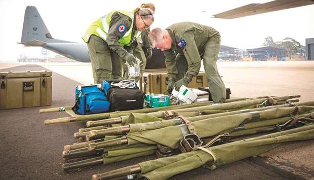 Sergeant Sheree Lewis (left) and Squadron Leader Justin Treble from No 3 Aeromedical Evacuation Squadron prepare equipment to load onto a C-130J Hercules prior to a mission to repatriate Australians who have been injured from the White Island volcanic eruption, at the Royal Airforce Base in Richmond, Australia.