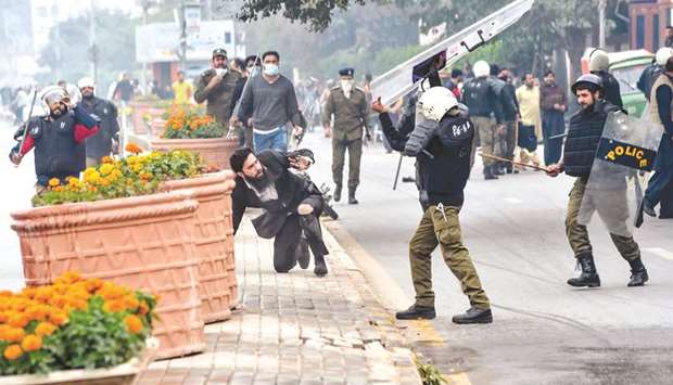 A policeman prepares to beat a lawyer (centre) following a clash between lawyers and doctors in Lahore yesterday.