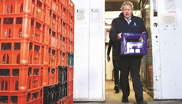 Prime Minister Boris Johnson carries a crate of milk to deliver to customers in Guiseley, Leeds, yesterday, on the final day of campaigning before a general election.
