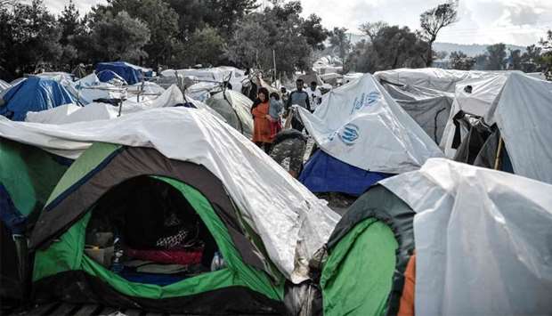 People walk among the tents in the Vial refugee camp, on the Greek island of Chios