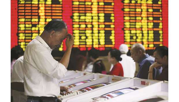 Investors look at computer screens showing stock information at a brokerage house in Shanghai (file). MSCI Incu2019s gauges of emerging market stocks and currencies dropped for the third successive week in the five days through Friday, capping their first November declines since 2016.