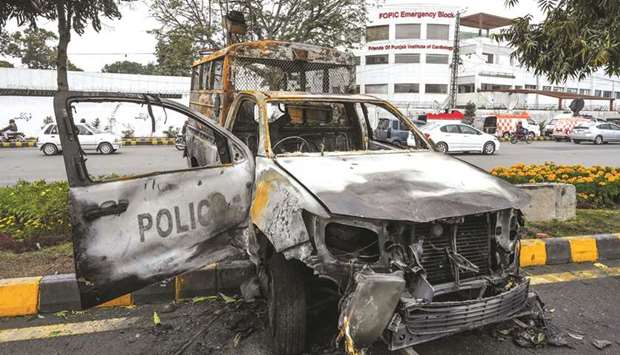 A burnt-out police van is seen outside the cardiac hospital in Lahore yesterday.