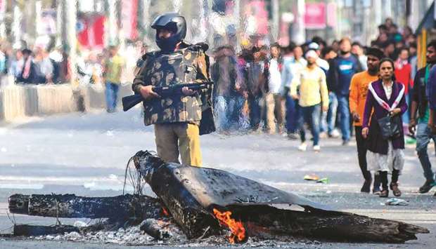 A security personnel stands guard near a fire on a road during a curfew in Guwahati yesterday following protests over the governmentu2019s Citizenship Amendment Bill (CAB).