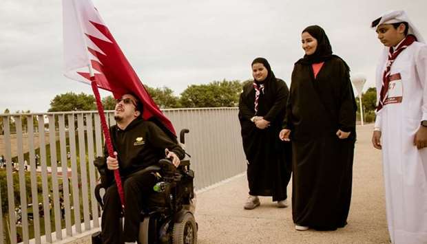 A Community Development employee holds the national flag as Machaille al-Naimi looks on during Team Qataru2019s Flag Relay