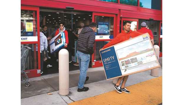 Shoppers carry televisions purchased from a store during Black Friday sales in Los Angeles (file). US retail spending was unexpectedly sluggish in November as consumers held back at the start of the holiday shopping period, according to a government report yesterday.