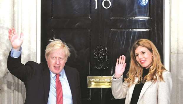 Prime Minister Boris Johnson and his girlfriend Carrie Symonds gesture as they arrive at 10 Downing Street on the morning after the general election in London yesterday.