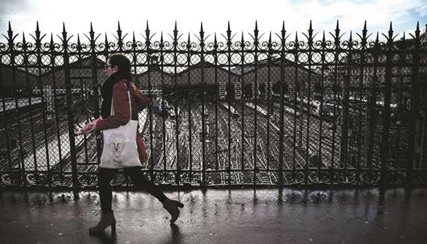A woman crosses a bridge over empty tracks leading to the Saint-Lazare railway station in Paris.