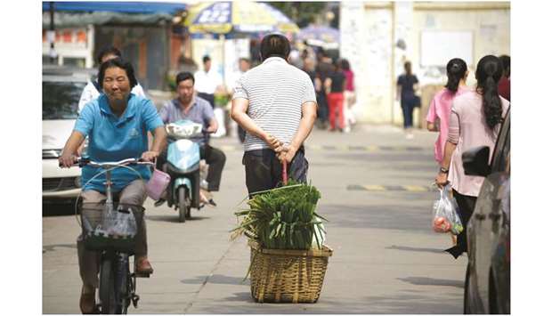 A man pulling a basket of leeks as he walks along a road near an open market in Beijing (file). The u201cthree critical battlesu201d against poverty, financial risks and pollution remain a priority for China in 2020.