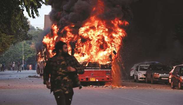 A man walks on a street as a bus is on fire following demonstration against the governmentu2019s Citizenship Amendment Bill (CAB) in New Delhi yesterday.