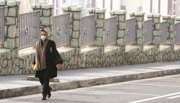 An Iranian woman, wearing a breathing mask walks down a street as a blanket of smog covers the city as heavy pollution hit Tehran, yesterday.