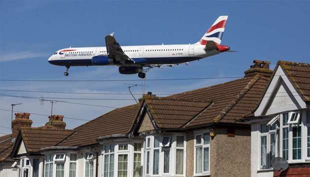 A passenger aircraft, operated by British Airways, a unit of International Consolidated Airlines Group passes residential rooftops as it prepares to land at London Heathrow Airport.