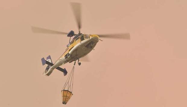 A helicopter prepares to drop water on a large bushfire in Bargo, southwest of Sydney, yesterday.