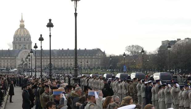 Soldiers salute the funeral convoy on Alexandre III Bridge in front of the Invalides monument in Paris, ahead of a ceremony to pay tribute to 13 French soldiers who died in a helicopter collision in Mali