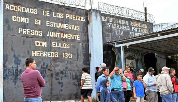 People gather outside the prison after several inmates were killed or wounded during a fight between rival gangs, in Tela