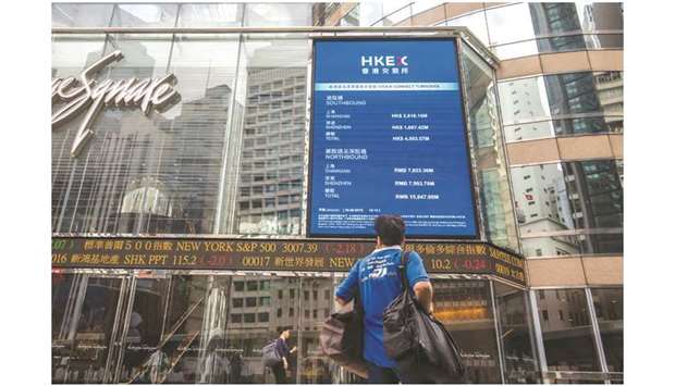 A pedestrian stands in front of an electronic ticker board and a screen displaying stock figures outside the Exchange Square complex, which houses the Hong Kong Stock Exchange, in Hong Kong (file). Hong Kong may be about to solve one critical step to boost its link to Chinau2019s mainland stock market, but sticky issues remain for MSCI Inc to further include the countryu2019s stocks in its coveted indexes.