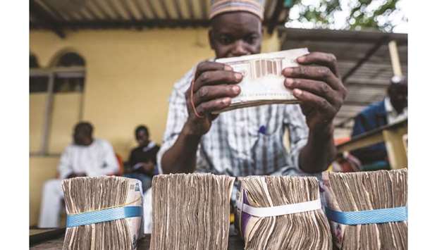 A currency dealer uses an elastic band to bundle naira banknotes in Lagos (file). Nigeriau2019s status as one of the worldu2019s best carry trades will probably last as long as central bank governor Godwin Emefiele keeps the naira stable.