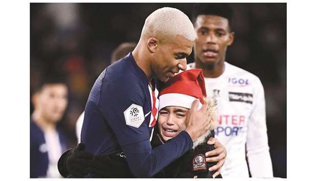Paris Saint-Germainu2019s French forward Kylian Mbappe (left) hugs a young fan during the Ligue 1 match against Amiens at the Parc des Princes stadium in Paris, France, on Saturday. (AFP)