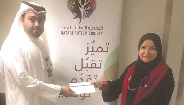 Hassan al-Jaidah, Head of Premium Banking at al khaliji hands over the cheque to Dr Manal al-Deeb, vice-president of Qatar Autism Society.