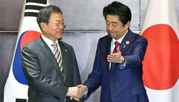 Japan's Prime Minister Shinzo Abe shakes hands with South Korea's President Moon Jae-in during their meeting in Chengdu, China