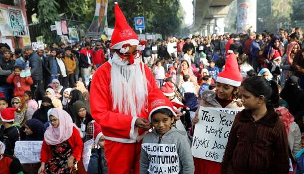 A man wearing a Santa Claus costume gives hats to kids during a protest against a new citizenship law, outside the Jamia Millia Islamia university in New Delhi