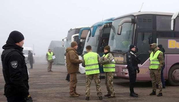 Ukrainian law enforcement officers and servicemen stand guard near buses for pro-Russian rebels before the exchange of prisoners of war (POWs) between Ukraine and the separatist republics near the Mayorsk crossing point in Donetsk region, Ukraine
