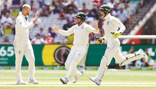 Australiau2019s Nathan Lyon (left), Joe Burns (centre) and Tim Paine celebrate the stumping of New  Zealandu2019s Henry Nicholls on the fourth day of the second Test at the MCG in Melbourne yesterday. (AFP)