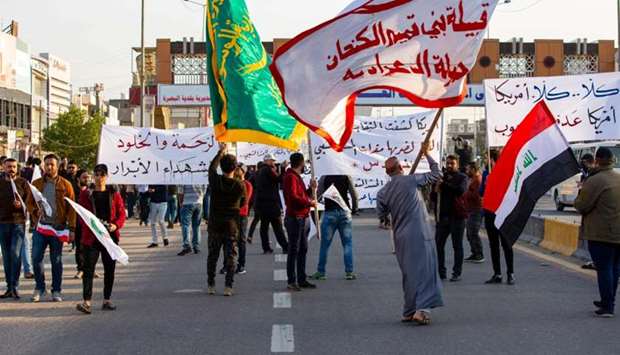 Iraqis wave Hashed Al-shaabi armed network flags in the southern city of Basra, during a demonstration to denounce the previous night's attacks by US planes on several bases belonging to the Hezbollah brigades near Al-Qaim, an Iraqi district bordering Syria