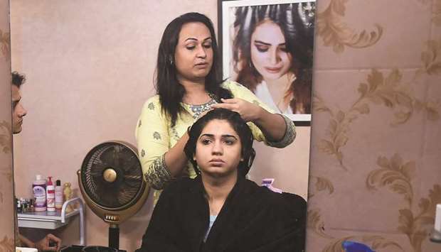 In this picture taken on October 15, 2019, transgender beautician Bebo Haider attends to a customer in her beauty parlour in Karachi.