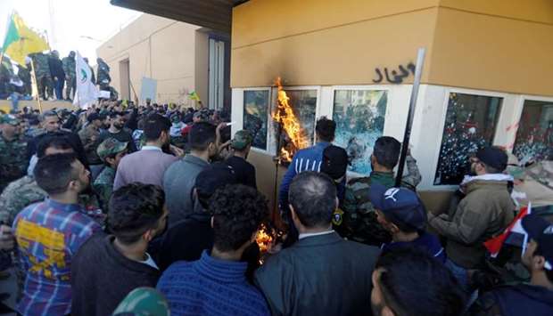 Protesters and militia fighters attack a reception room of the US Embassy, during a protest to condemn air strikes on bases belonging to Hashd al-Shaabi (paramilitary forces), in Baghdad