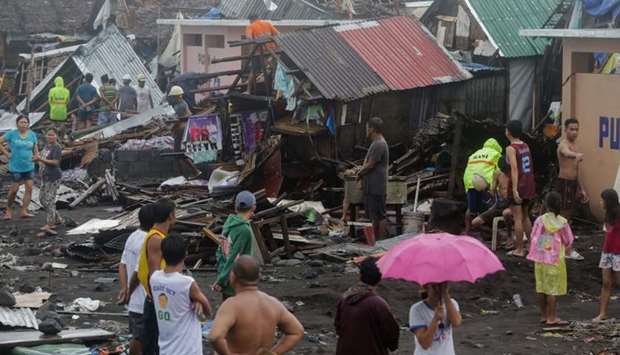 Residents stand among their damaged houses after Typhoon Kammuri hit Legazpi City, Albay, Philippines, yesterday