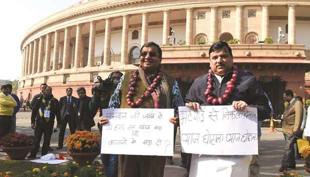 Aam Aadmi Party (AAP) parliament members Sanjay Singh (right) and Shushil Gupta wearing garlands made out of onions and display placards to protest against onion price hike at the Parliament House in New Delhi yesterday.