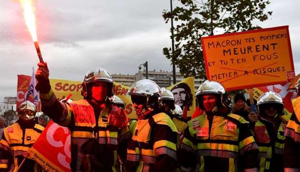 Firefighters hold placards reading messages such as ,Macron your firefighters are dying and you don't care, high-risk job, and smoke-bomb as they take part in a demonstration to protest against the pension overhauls, in Marseille, southern France