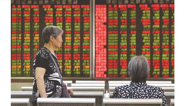 Women talk in front of a screen showing stock prices at a securities company in Beijing. Shanghai bourse closed 0.7% higher at 2,899.47 points yesterday.