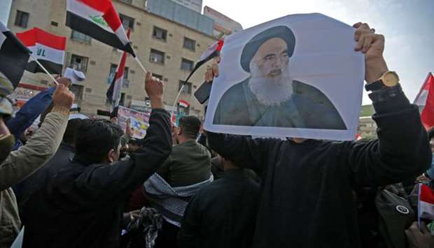 Iraqi supporters of the Hashed Al-shaabi armed network, carry a pictures of the country's top cleric, Grand Ayatollah Ali Sistani, as they demonstrate in the capital Baghdad's Tahrir Square yesterday