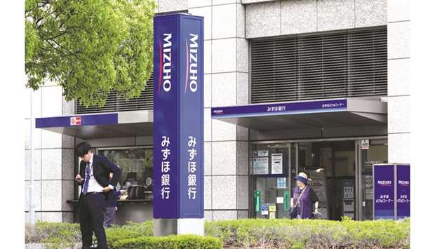 Pedestrians walk past a branch of Mizuho Bank in Tokyo. The top three lenders providing loans or investment banking services to companies that acknowledge the risks of climate change are Japanese banks Mizuho, Mitsubishi UFJ Financial Group and the Sumitomo Mitsui Banking Corp.