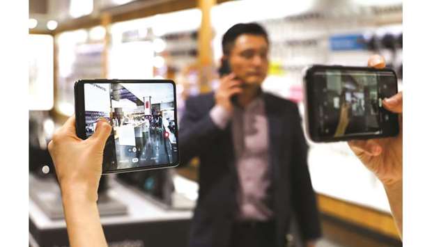 A customer takes a photograph of a Samsung Electronics Galaxy Fold smartphone using her mobile phone at the companyu2019s Du2019light flagship store in Seoul. The Korean company is preparing the biggest overhaul to the cameras on its flagship phones for next year, according to people familiar with the companyu2019s plans.