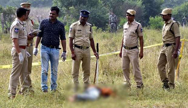 Police personnel stand next to the body of a man at the site where Police officers shot dead four detained gang-rape and murder suspects in Shadnagar, some 55 kilometres (34 miles) from Hyderabad