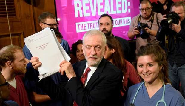 Britain's opposition Labour Party leader Jeremy Corbyn holds up documents as he poses for a picture with NHS staff, after a press briefing during a general election campaign event in London, Britain
