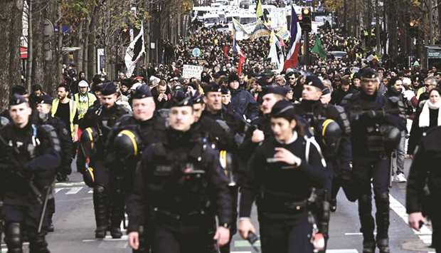 Anti-riot police personnel walk ahead of members of the u2018yellow vestu2019 movement demonstrating in Paris.