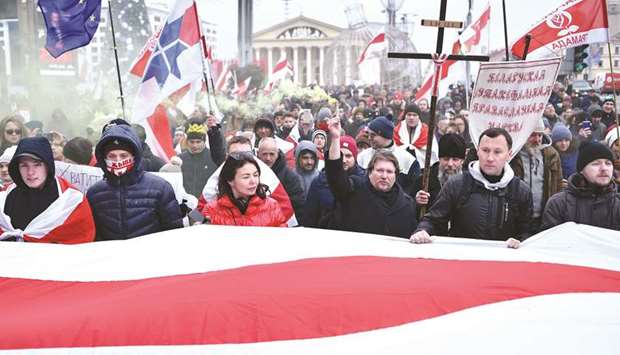 People carry a giant Belarusian white-red-white flag and anti-integration banners during a rally in Minsk against a Belarusian-Russian integration project.