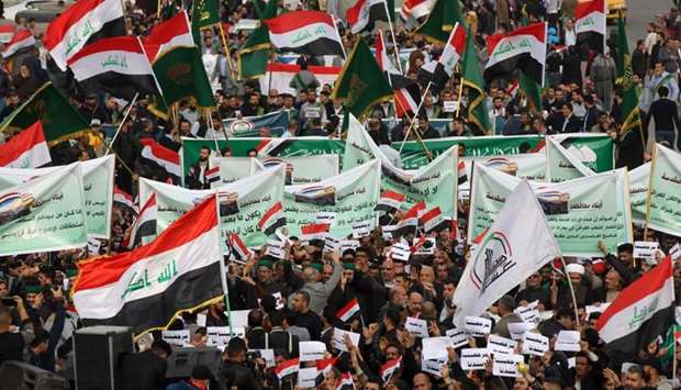 Iraqi demonstrators wave national flags and carry banners as the take part in an anti-government demonstration in the capital Baghdad's Tahrir Square Friday