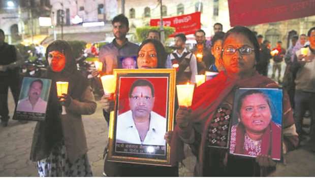 Survivors and relatives of victims of the Bhopal gas accident hold photos of the victims during a candlelight vigil. PICTURE: Sanjeev Gupta/EPA