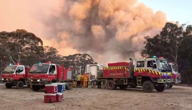 Smoke of fire rise next to firefighting vehicles as bushfires burn in Newnes Plateau, New South Walles, Australia