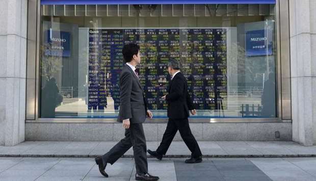 Pedestrians walk pass past an electronic stock board outside a securities firm in Tokyo. The Nikkei 225 closed 0.2% down at 26,756.24 points yesterday.